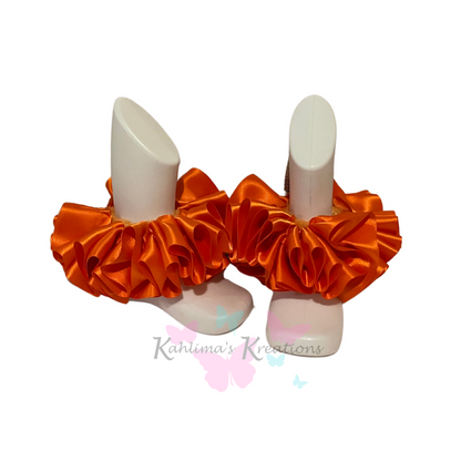 Pair of orange ruffled anklets on white background