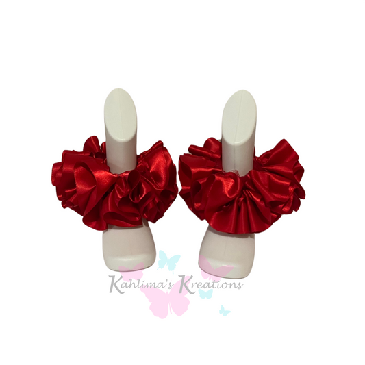 Pair of red ruffled anklets on white background